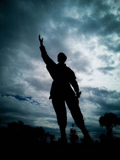 Low angle view of silhouette statue standing against sky