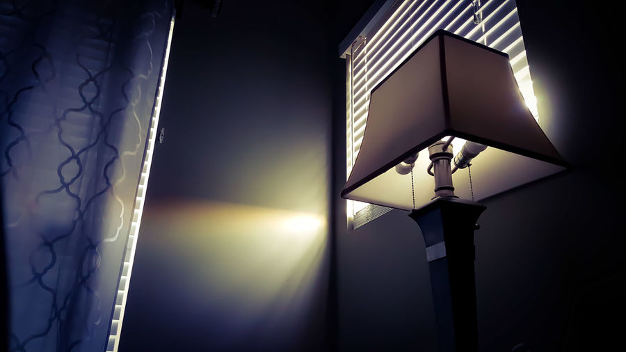 Low angle view of lamp in room against window