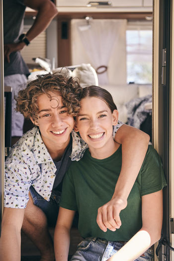 Portrait of smiling siblings sitting in camper trailer