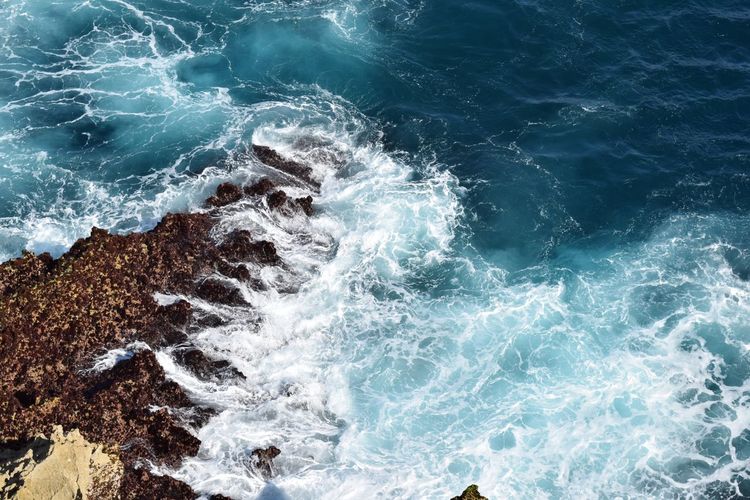 Aerial view of waves splashing on rocks