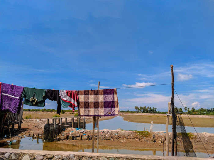 Clothes drying on beach against blue sky