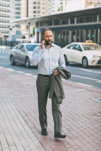 Businessman walking on footpath in city