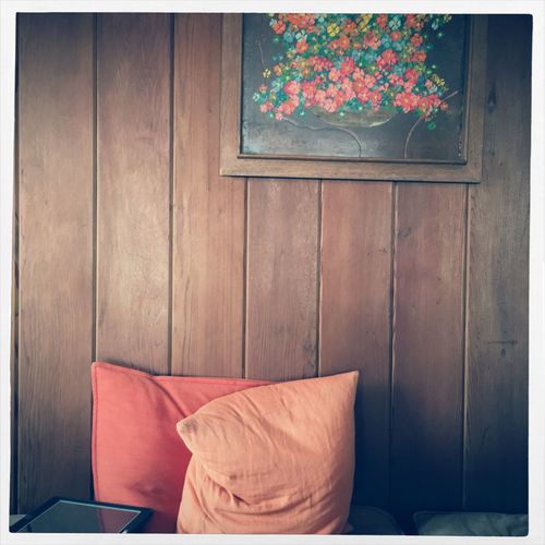 Pillows on bed against wooden wall at home