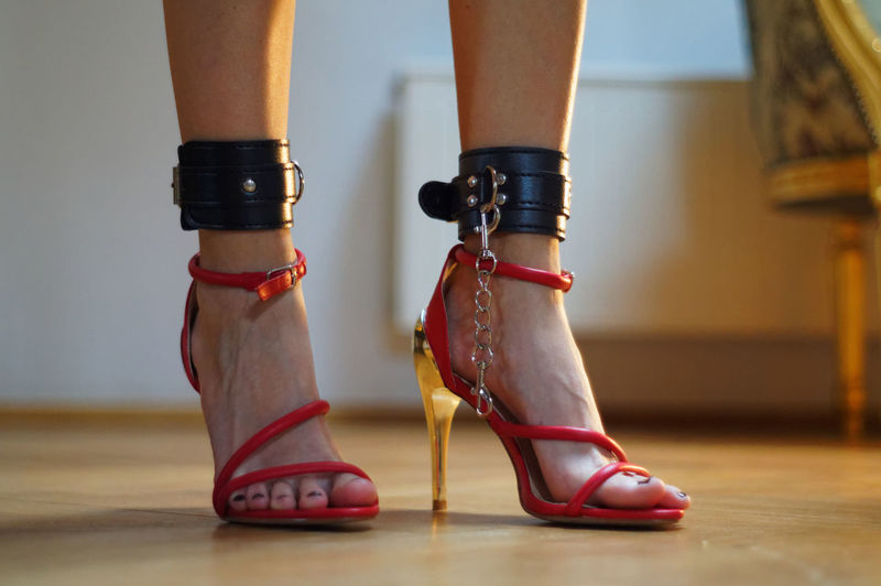 Low section of woman wearing fetish belt and high heels