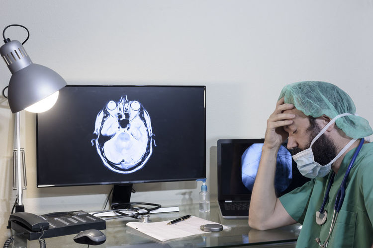 Worried doctor with head in hands sitting at table