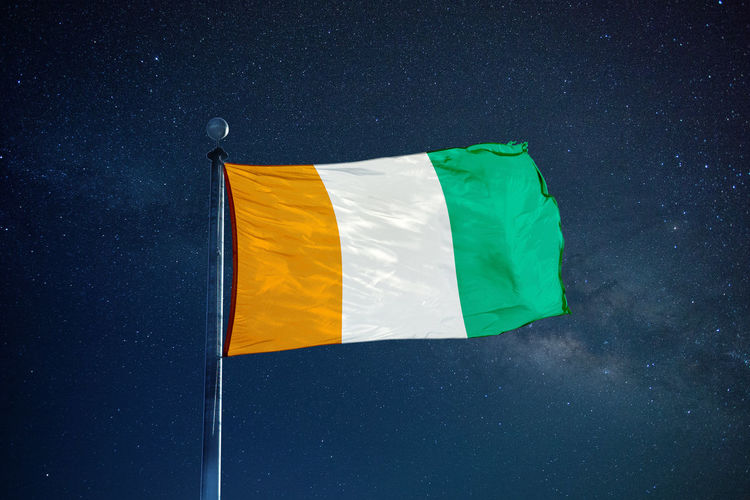 Low angle view of ivorian flag against star field sky