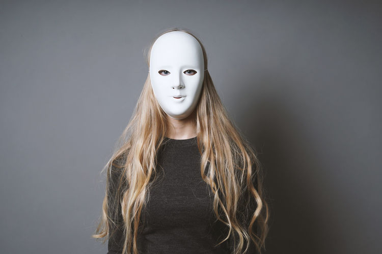 Portrait of young woman standing against white background