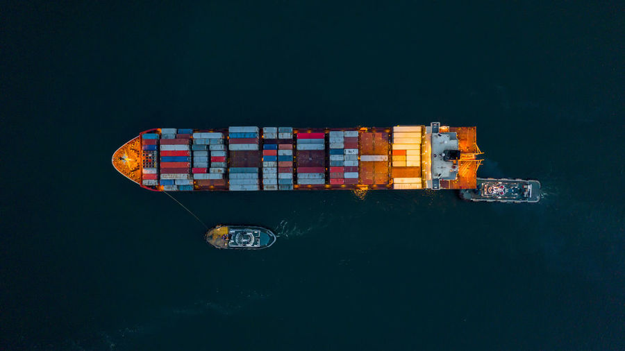 Aerial top view container ship at night, freight shipping maritime vessel, global business supply.