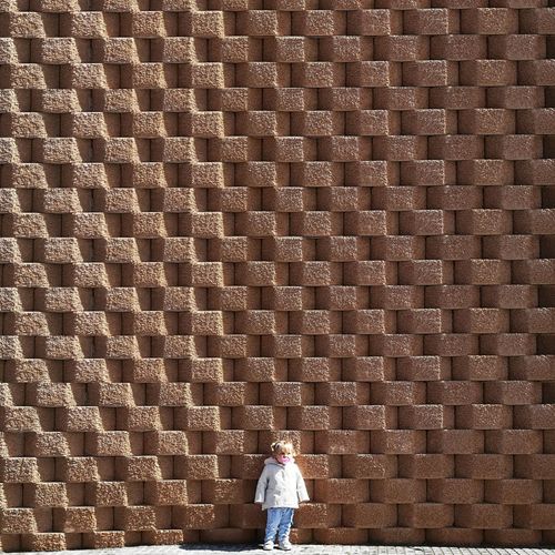 Girl standing against brick wall