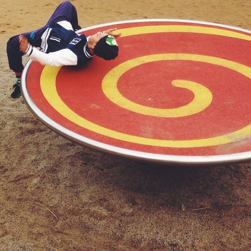 High angle view of boy playing on roundabout at playground