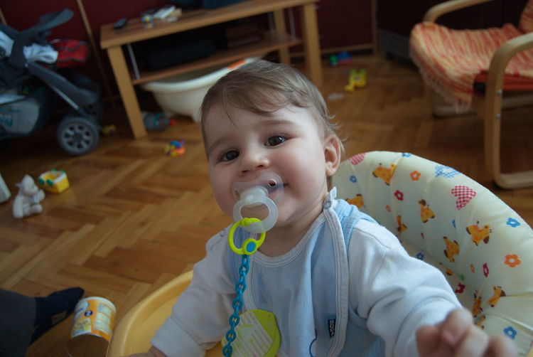Portrait of cute boy with pacifier in mouth at home