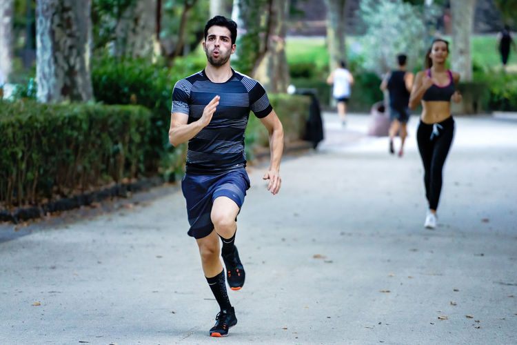 Full length of young man running on footpath
