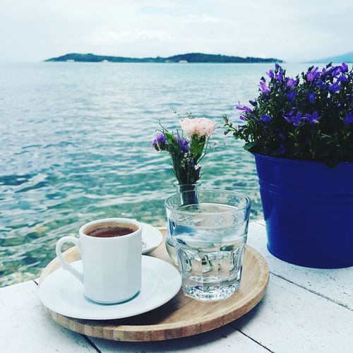 Close-up of turkish coffee with vase and potted plant by sea