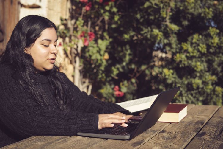 Young woman using laptop while sitting at park
