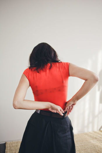 Rear view of woman standing against wall at home