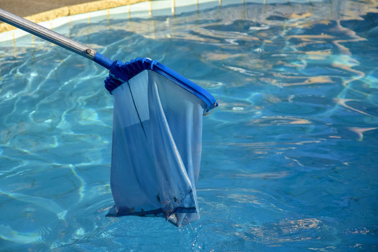 Cleaning pool from garbage with special net. clear water with blue tint.