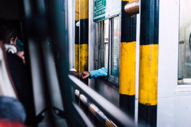 Cropped image of man taking payment at toll booth seen from window