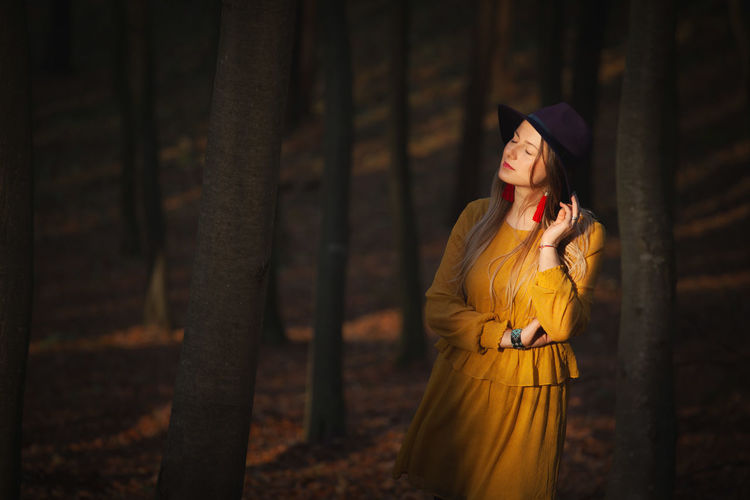 Woman wearing hat while standing in forest during autumn