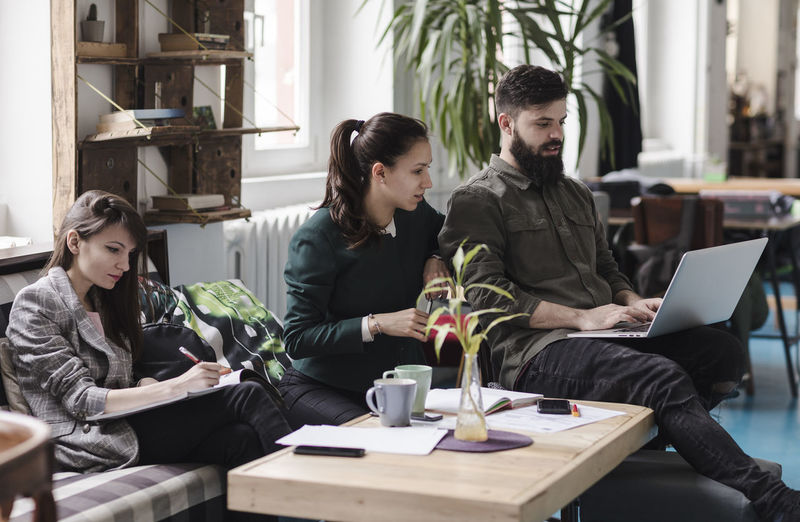 young colleagues Friends Adult Business Casual Clothing Collègues Communication Computer Connection Crew Friendship Group Of People Indoors Laptop Sitting Table Team Technology Together Togetherness Using Laptop Wireless Technology Women Young Adult Young Men Young Women