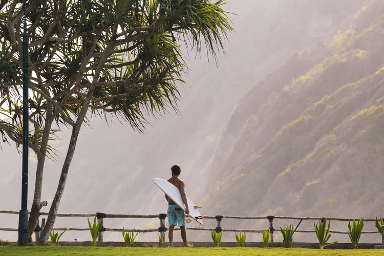 Young man walking and carrying surfboard