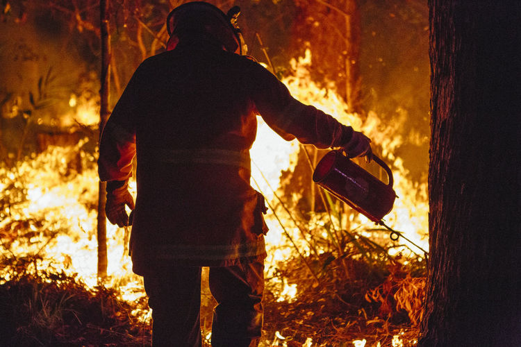 A firefighter conducting a controlled burn with a drip torch