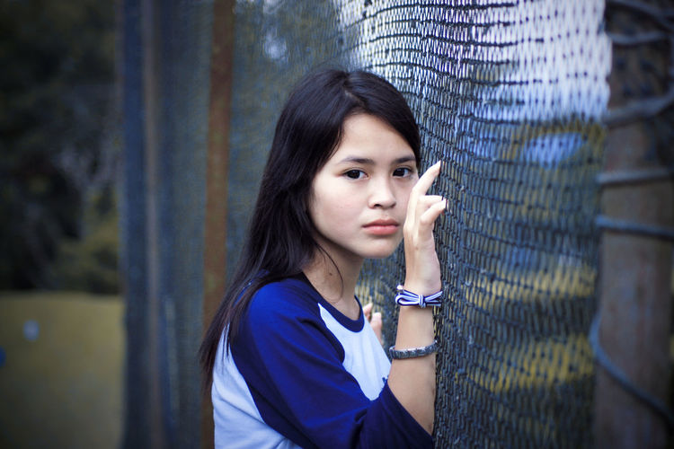 Portrait of young woman leaning on fence