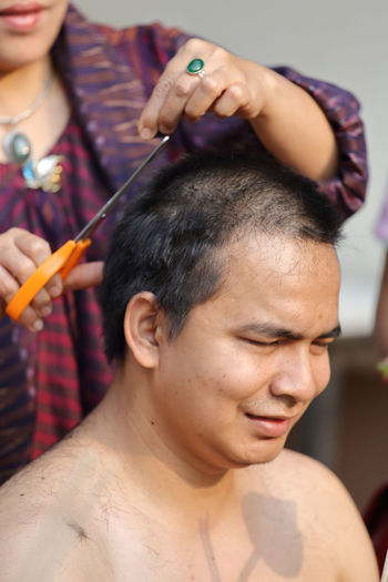 Woman cutting hair of man during ordination