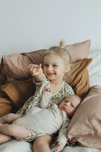 Girl with newborn sibling on bed