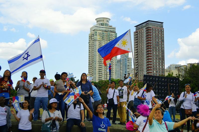 People on street amidst buildings in city against sky