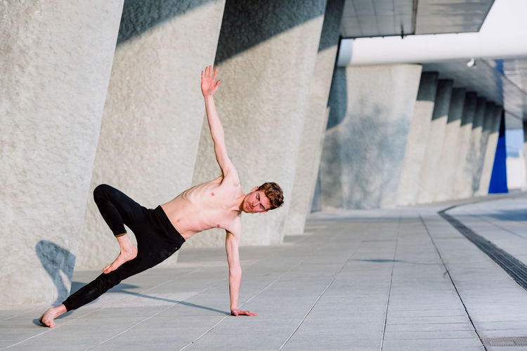 Full length of man stretching against wall