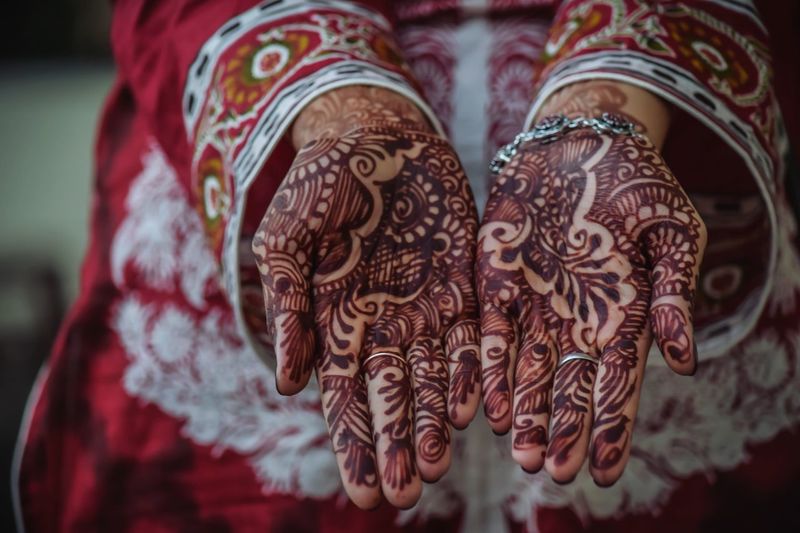 Midsection of bride showing henna tattoo on hands