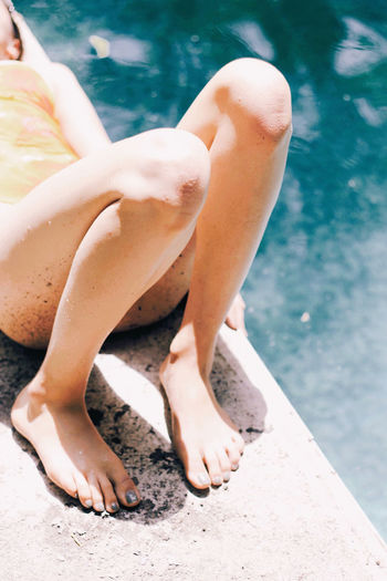 Low section of woman sitting in swimming pool