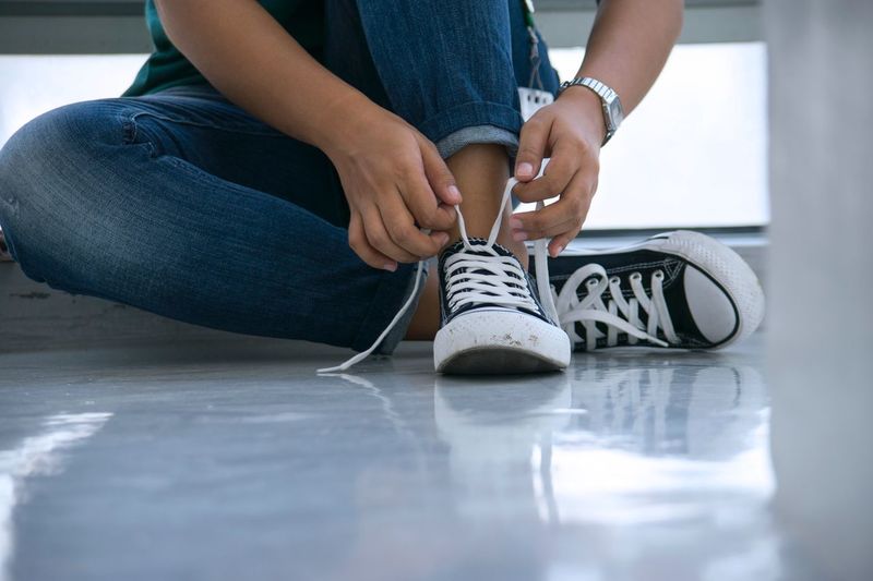 Low section of woman tying shoelace on floor