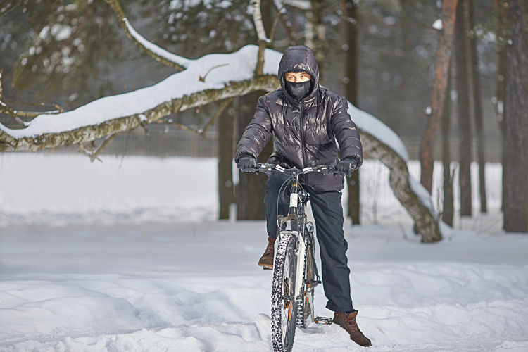 Active winter recreation. a teenager in a buff and black clothes rides a bike in winter
