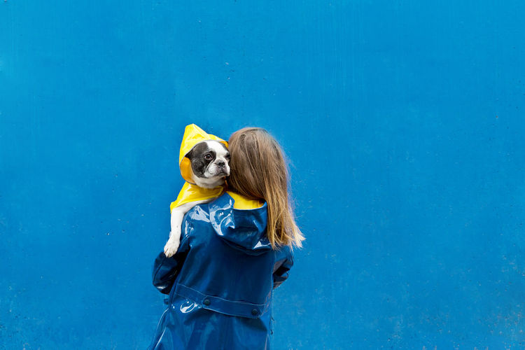 Woman with dog standing against blue background