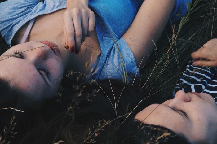 High angle view of female friends lying on grassy field