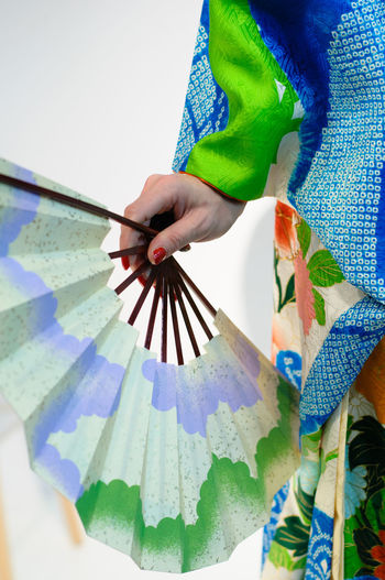 Low angle view of hand holding multi colored umbrella