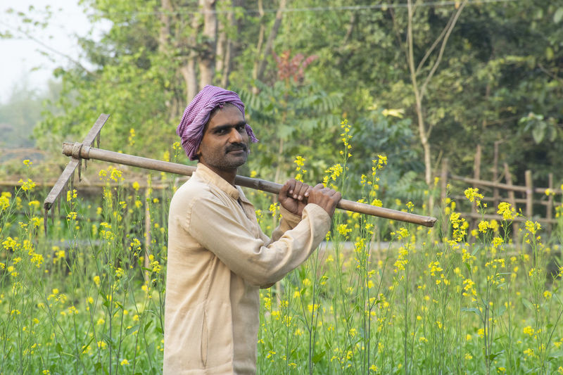 Farmer holding spade on his shoulder at farm land