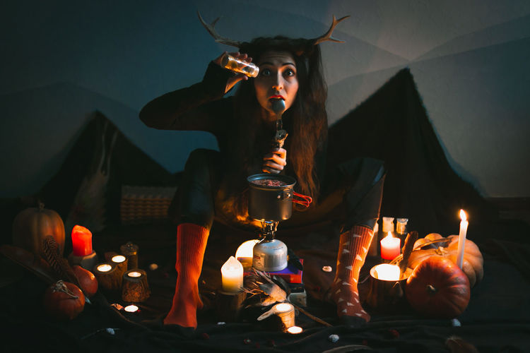 Close up woman witch with horns making soup more flavorful portrait picture