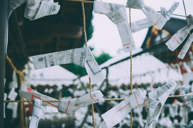 Close-up of fortune papers tied up on rope outside shrine