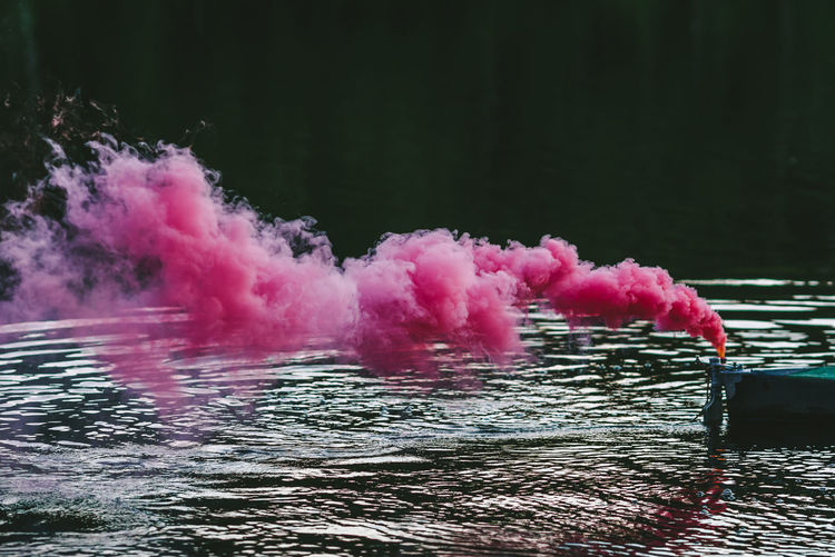Close-up of pink smoke above lake