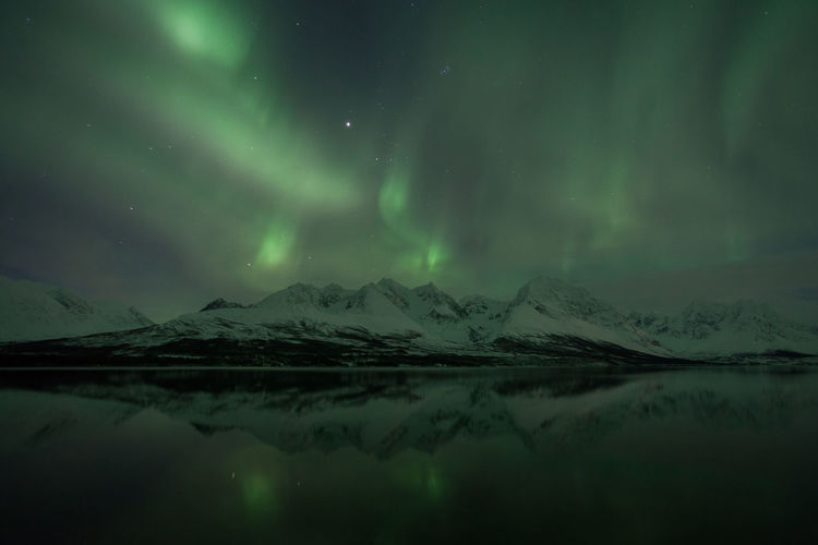 Scenic view of aurora borealis over lyngen alps and lake