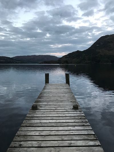 Pier over lake against cloudy sky