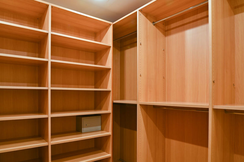 Wardrobe room in an apartment with wooden cabinets for storing clothes.