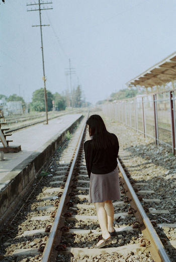 Rear view of woman walking on railroad tracks