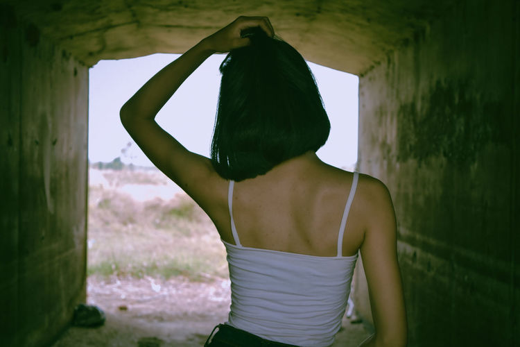 Rear view of woman standing against wall