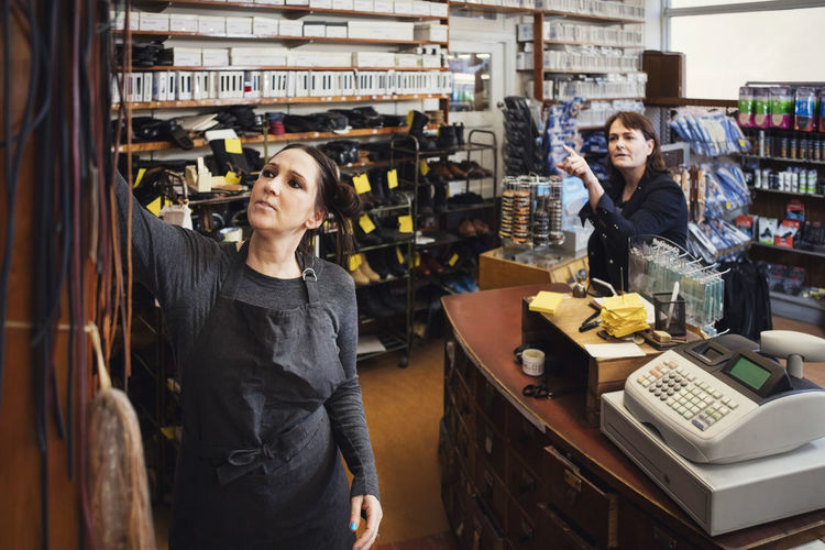 Shoemaker assisting female customer at repair store