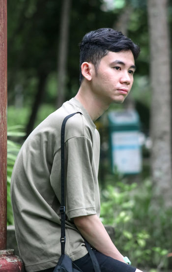 Young man looking away while standing outdoors