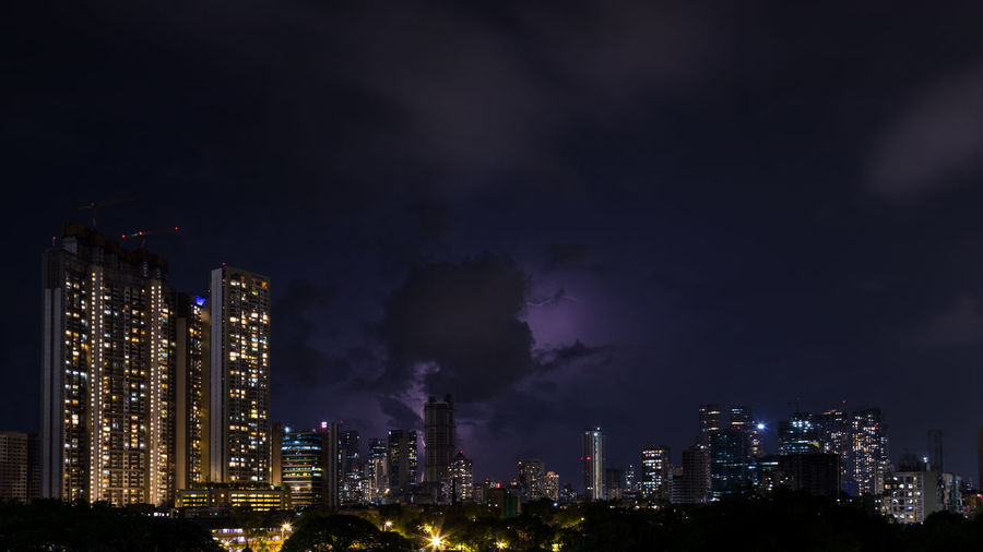 Illuminated buildings in city against sky at night