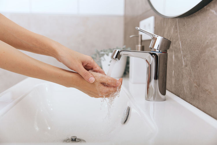 Cropped hands washing faucet